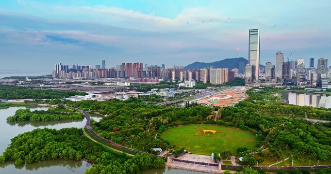 Aerial view of lush green city park and modern skyscraper skyline in the financial district of Shenzhen, China.