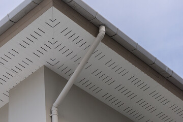 Sleek white gutter system against light sky © Rattanachat