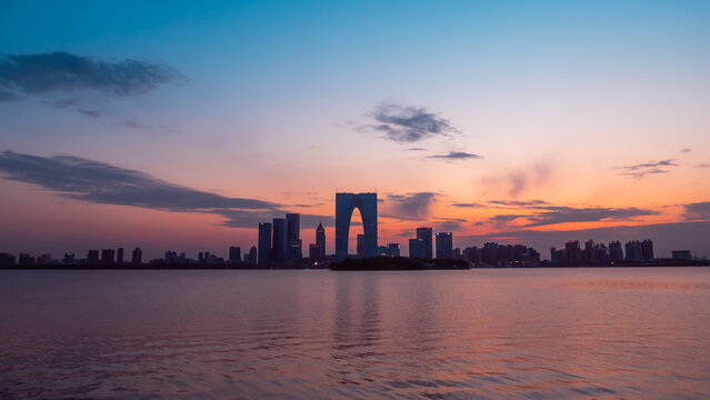 Evening skyline of Suzhou Gate of the Orient at dusk over lake.