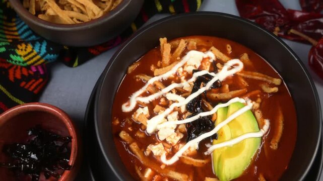 Close up of authentic Mexican tortilla soup decorated with avocado slices and cream
