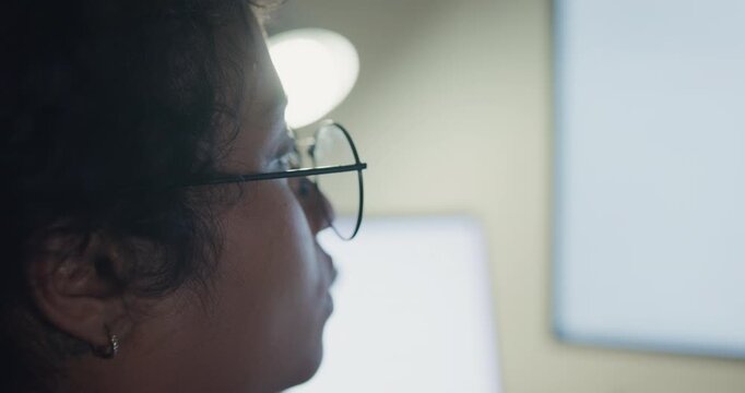 Close-up young Black female programmer coding AI software on multiple screens in night office. Network security, cybersecurity, machine learning, working late, overtime, robotics automation concept.