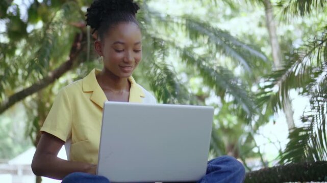 Young woman working on laptop computer outdoors
