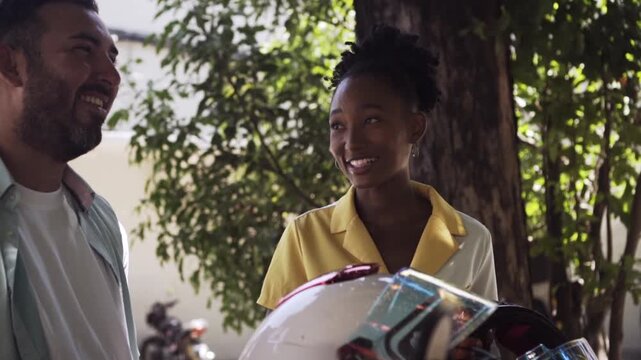 Interracial couple holding motorcycle helmets and smiling