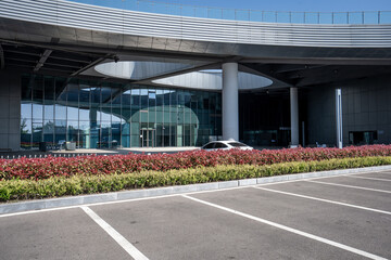 Naklejka premium Modern building entrance with glass curtain wall and empty parking lot under clear sky
