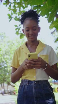 African american woman smiling while using smartphone outdoors