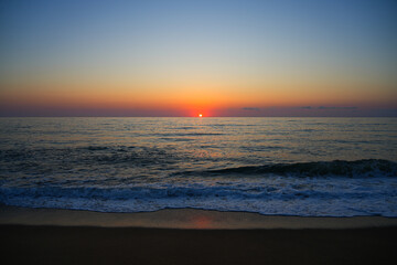 Obraz premium Sunset over the mediterranean sea with breaking wave and white foam on Piscinas beach in Sardinia, Italy