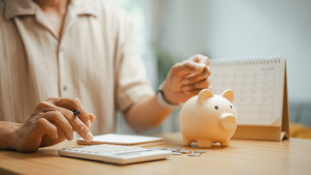 Person managing a budget with a calculator, piggy bank, and monthly planner, representing personal finance, savings goals, expense tracking, and smart financial planning for future stability.