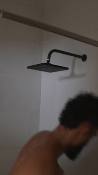 Bearded adult male washing body and hair in the shower