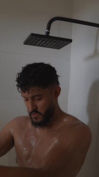 Bearded hispanic male taking shower and washing body