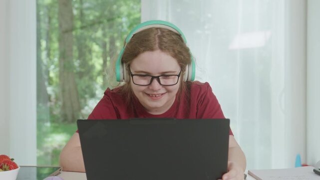 Learning at desk with laptop. Child learning wears wireless headphones. Learning online uses computer screen. Learning homework fits school lesson.