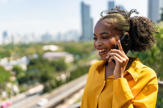 African American woman talking on mobile phone while relaxing in the city. 