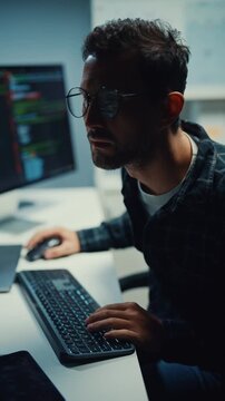 Vertical Screen : Young Caucasian male programmer write code on computer in office at night. AI technology, cybersecurity, software developer, freelance innovation, database system, digital network.