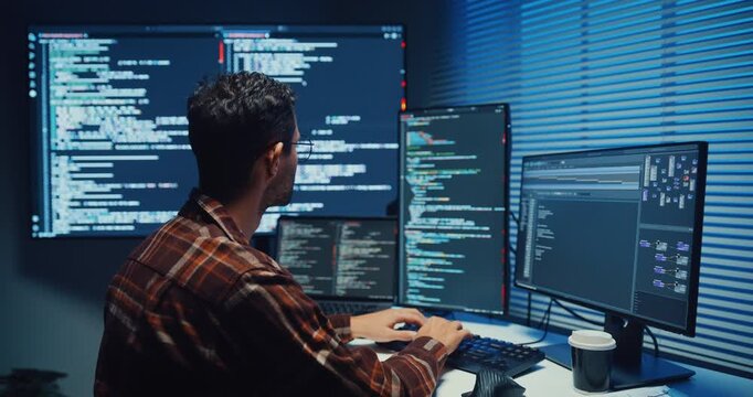 Young Caucasian male programmer write code on computer in home office at late night. AI technology, cybersecurity, software developer, freelance innovation, database system, digital network concept.