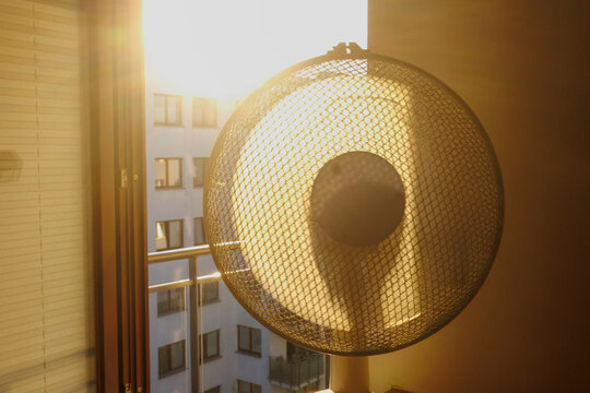 Electric fan ventilating a room on a hot summer morning.