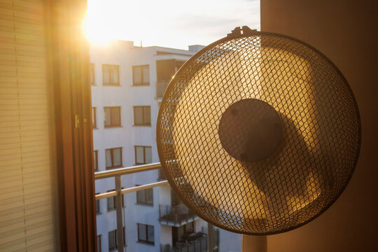 Electric fan ventilating a room on a hot summer morning.