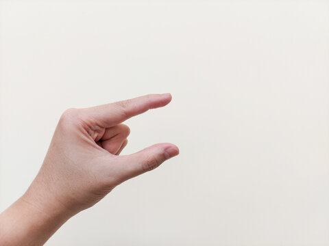 A pinching or measuring gesture isolated on white background with copy space, symbolizing precision, measurement, comparison, estimation, tiny size, small amount, dexterity, hand motion, motor skill.