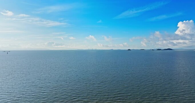 Panoramic view of the blue sea and distant bridge under a clear blue sky in Zhuhai, China