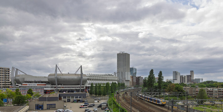 Eindhoven, Netherlands, June 13, 2026. Panoramic cityscape showing the PSV Philips Stadion on the left alongside the city's modern skyscraper skyline and railway.