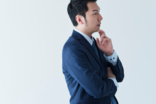 考えるポーズのスーツ姿の30代男性ビジネスマン