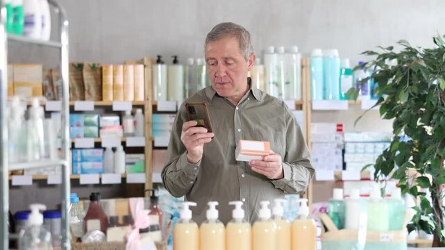 Interested senior male customer scanning QR code on pills packaging with phone to read usage instructions, reviews, or learn about correct dosage before buying in drugstore