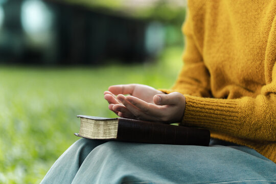 The young woman is praying. Concepts of offering prayer and praise to God. prayer and praise with the Bible.