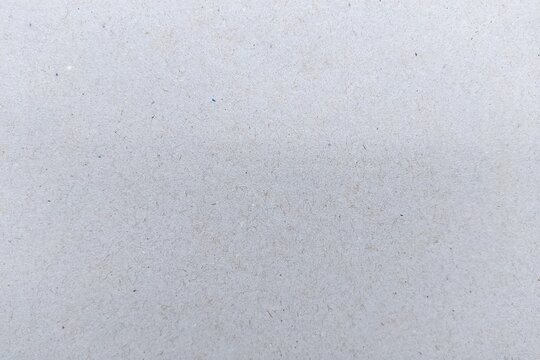 Recycled light grey paper texture background with visible fibers, macro surface of grey cardboard kraft paper