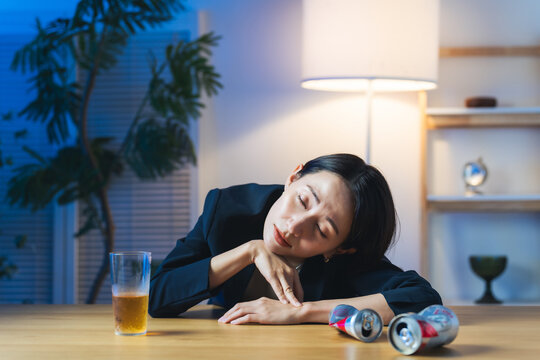 暗い部屋で酔い潰れる女性。お酒、ショック、がっかり、落ち込む、やけ酒、酔う、アルコール、居酒屋