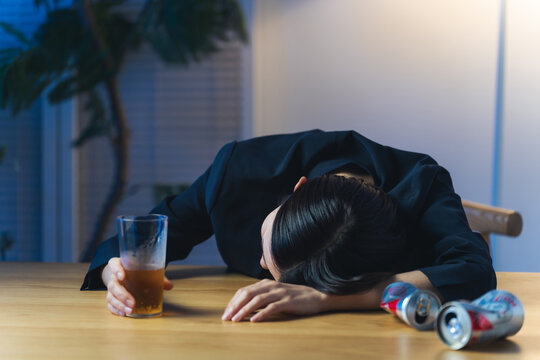暗い部屋で酔い潰れる女性。お酒、ショック、がっかり、落ち込む、やけ酒、酔う、アルコール、居酒屋