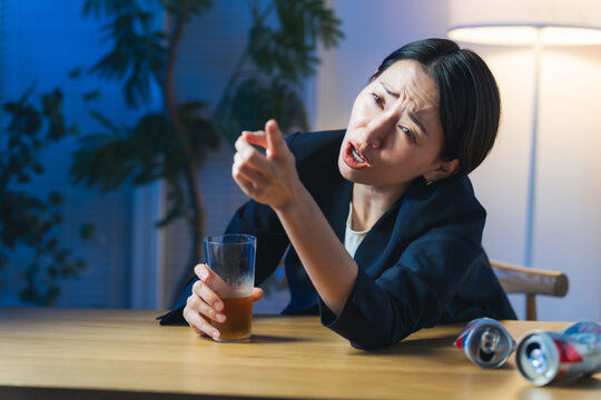 お酒を飲んで文句を言う女性。お酒、ビール、居酒屋、絡む、愚痴、くだを巻く、酔っ払い、迷惑
