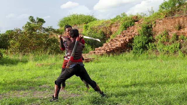 Traditional Thai Warriors Practicing Sword Fighting Near Ancient Ruins