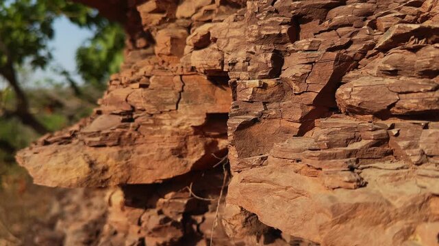 Slow jib down movement across exposed sedimentary rock layers revealing weathered geological textures natural fractures and the intricate structure of a rugged cliff formation