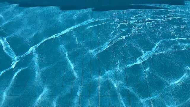 Sunlight reflecting on the blue tiles of a swimming pool.