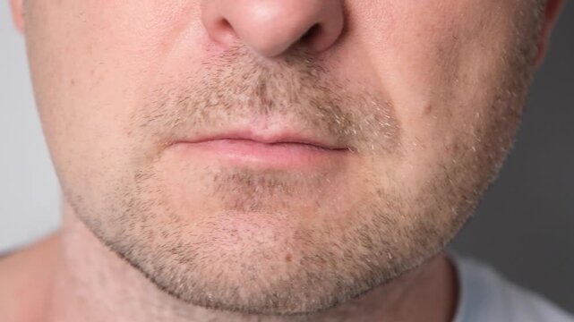 Close-up of a man pressing lips together while shaking head no. Facial expression conveying disagreement, refusal, disapproval, rejection, determination and negative response