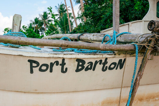 Traditional Filipino outrigger boat with blue rope and bamboo poles on a sandy beach in Port Barton, Philippines.