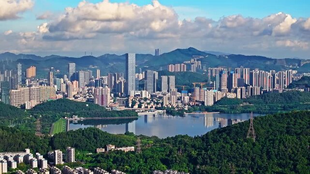 Aerial view of modern city skyline with a large reservoir and lush green mountains in Shenzhen, China