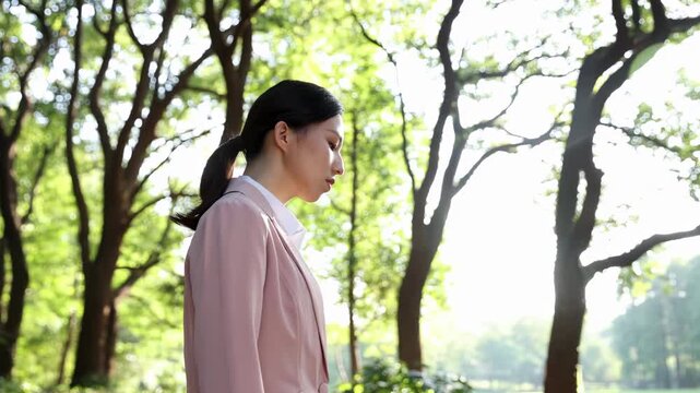 Confident businesswoman in suit walking on a path in lush green park during her break, enjoying nature embrace finding peace amidst urban landscape green forest right next to modern office building