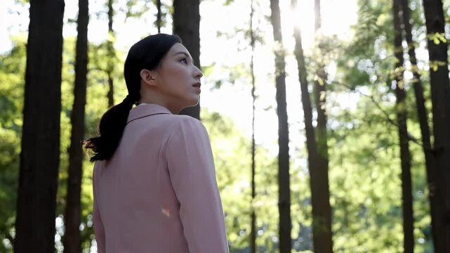Smiling businesswoman in suit walking on a path in lush green park during her break, enjoying nature embrace finding peace amidst urban landscape green forest right next to modern office building