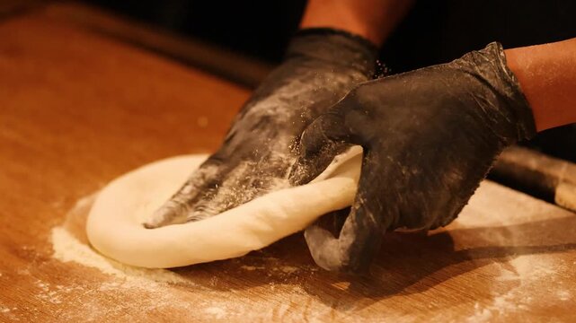 Chef in Black Gloves Kneading Fresh Pizza Dough on Wooden Table