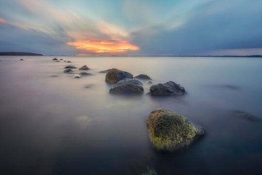 Calm ocean water with rocks at sunset in a peaceful sea