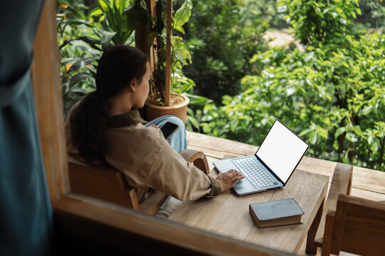 Businesswoman is working at her computer on the balcony of her homestay. The working woman is working on her laptop during her vacation. checking work, shopping online, working from home.