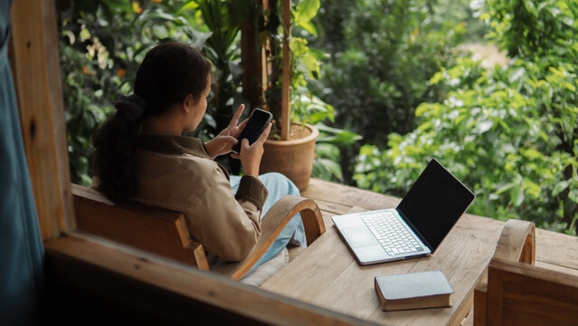 Businesswoman is working at her computer on the balcony of her homestay. The working woman is working on her laptop during her vacation. checking work, shopping online, working from home.