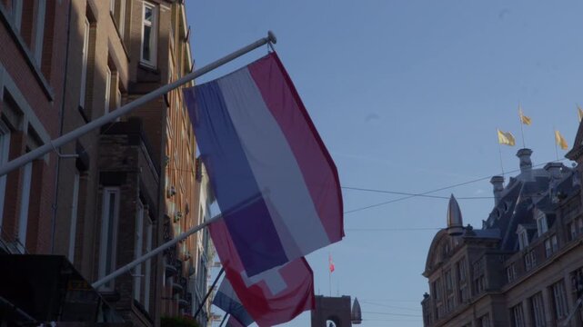 Low angle view of Netherlands and Swiss flags fluttering above Amsterdam streets