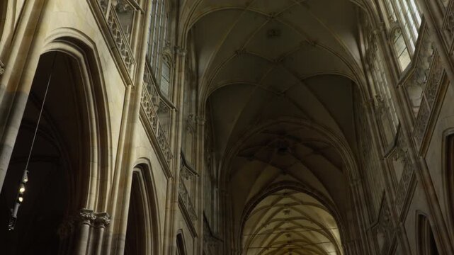 Pan up from stained glass windows to vaulted ceiling of historic church in Prague