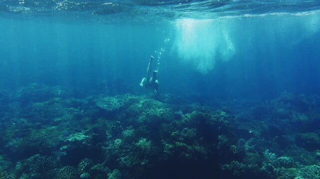Woman snorkeling and diving in clear turquoise ocean water