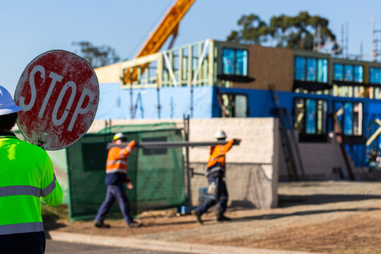 traffic controller holding stop sign with building worksite in background