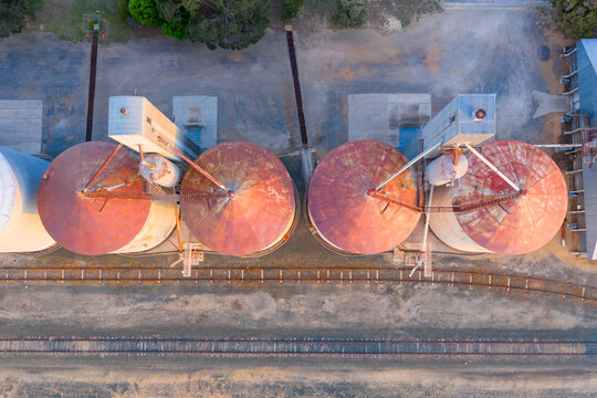 Aerial view over the top of a row of grain silos along a regional railway line