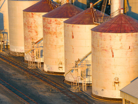 Aerial view of golden sunshine on a row of grain silos along a regional railway line