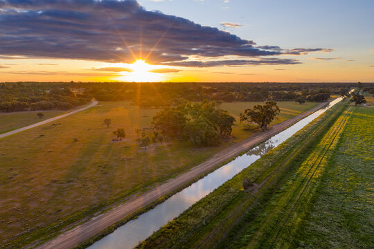 Aerial view of a golden sunset over over an irrigation channel and farmland