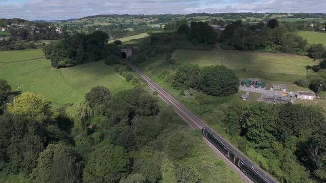 Aerial shot of train entering Box tunnel, in lush Wiltshire countryside on a sunny day