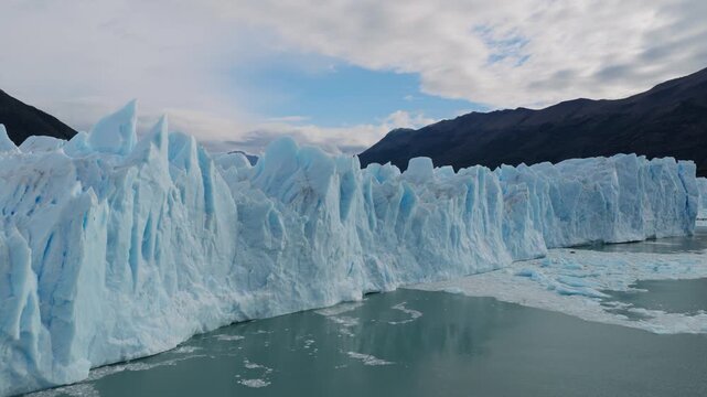 Perito Moreno Glacier in Los Glaciares National Park, Santa Cruz, Argentina, featuring towering blue ice formations above Lago Argentino, drone forward oblique flyover shot.